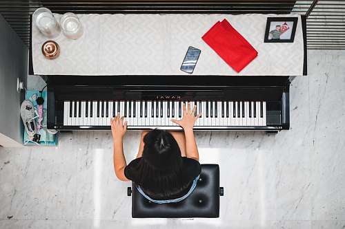 music woman playing piano near white wall inside room piano
